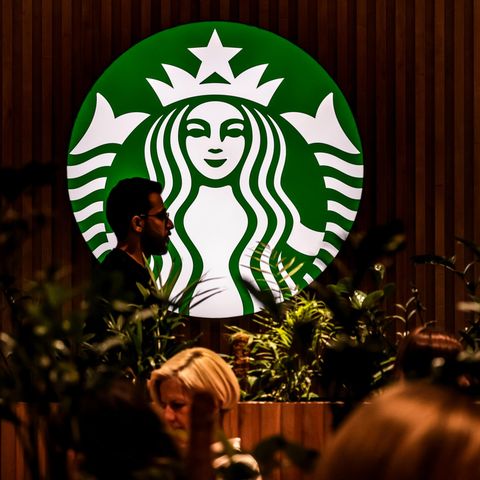 Eine Person läuft vor dem leuchtenden Starbuckslogo