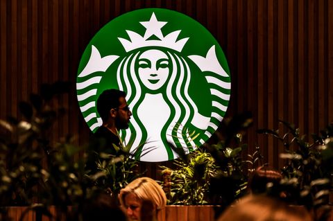 Eine Person läuft vor dem leuchtenden Starbuckslogo