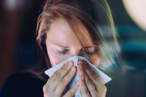 Immunsystem: Eine Frau niest in ein Papiertaschentuch