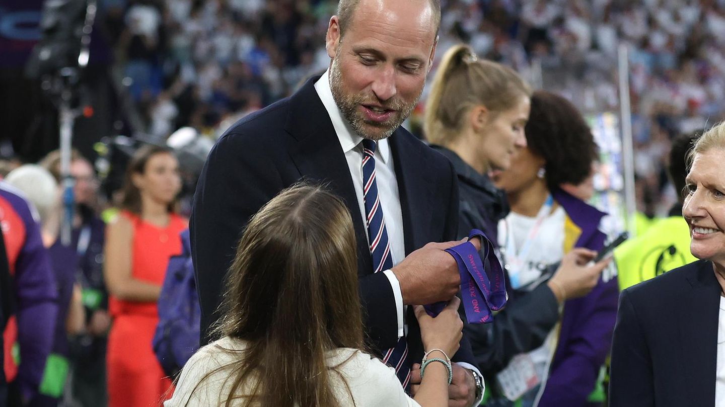 Prinz William hält die Medaillen in der Hand, die er übergeben soll, Charlotte blickt zu ihm auf
