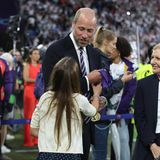 Prinz William hält die Medaillen in der Hand, die er übergeben soll, Charlotte blickt zu ihm auf