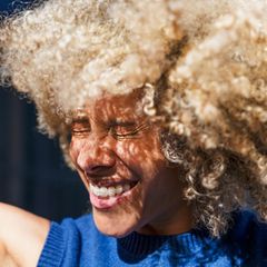 Lachende Frau vom Sonnenlicht geblendet