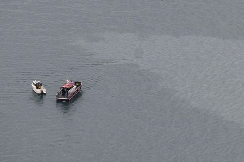 Zwei Boote treiben neben einem Ölfilm auf dem Vierwaldstättersee in der Schweiz