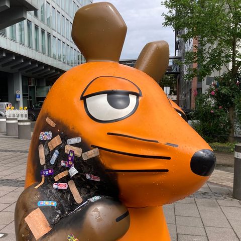 Pflaster kleben auf dem verbrannten Hald der Maus-Figur vor dem WDR in Köln