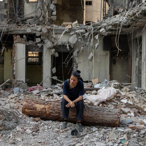 A woman sits in a destroyed building in Iran
