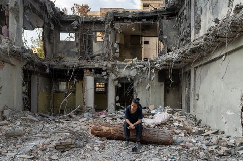 Eine Frau sitzt in einem zerstörten Gebäude im Iran