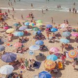 Urlauber und ihre bunten Sonnenschirme über den Strand verteilt