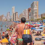 Ein Mann sucht einen Liegeplatz am überfüllten Strand von Benidorm