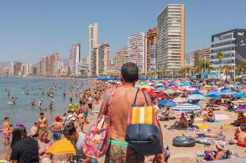 Ein Mann sucht einen Liegeplatz am überfüllten Strand von Benidorm