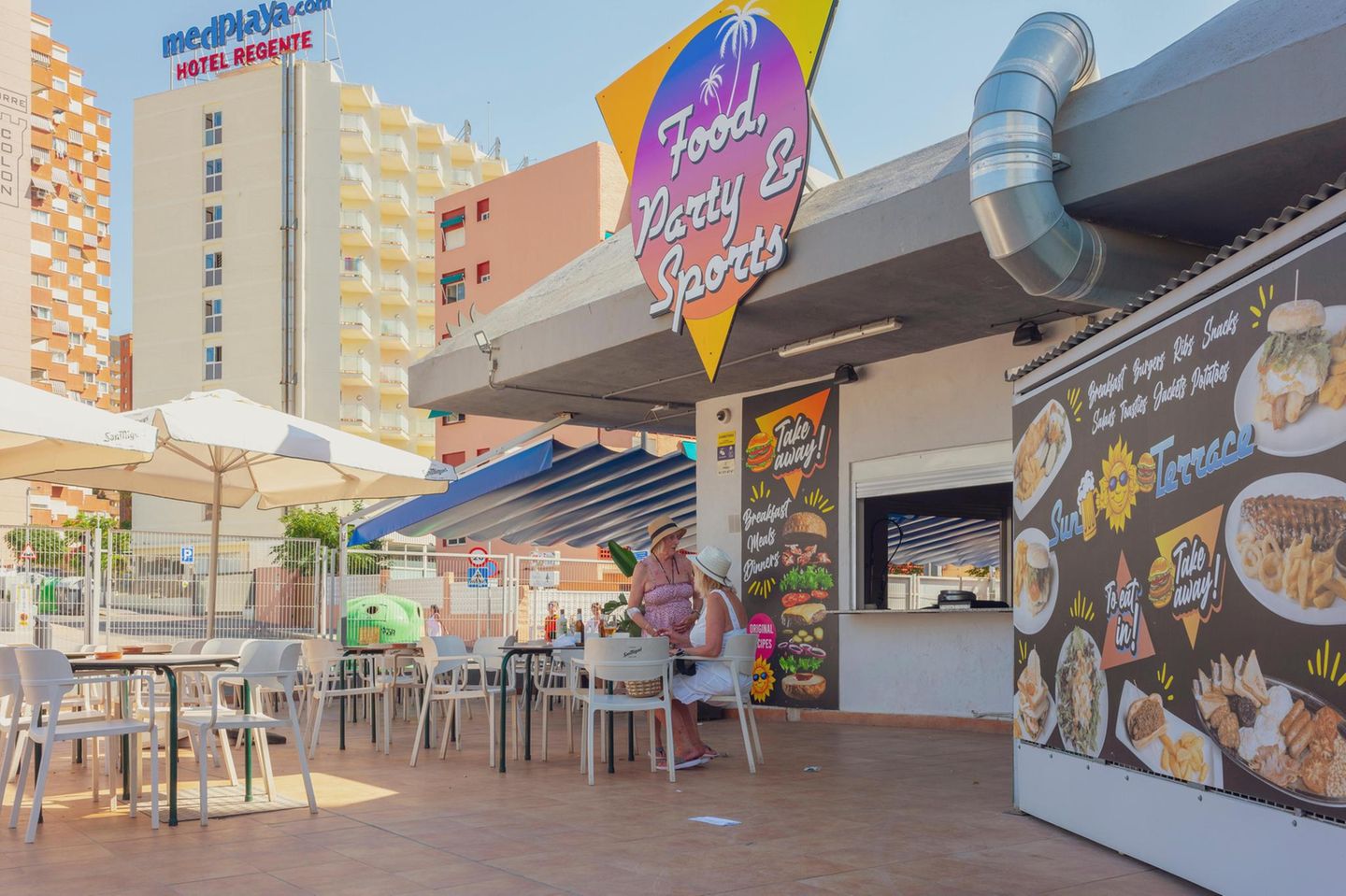 Urlauberinnen sitzen auf der Terrasse eines Restaurants