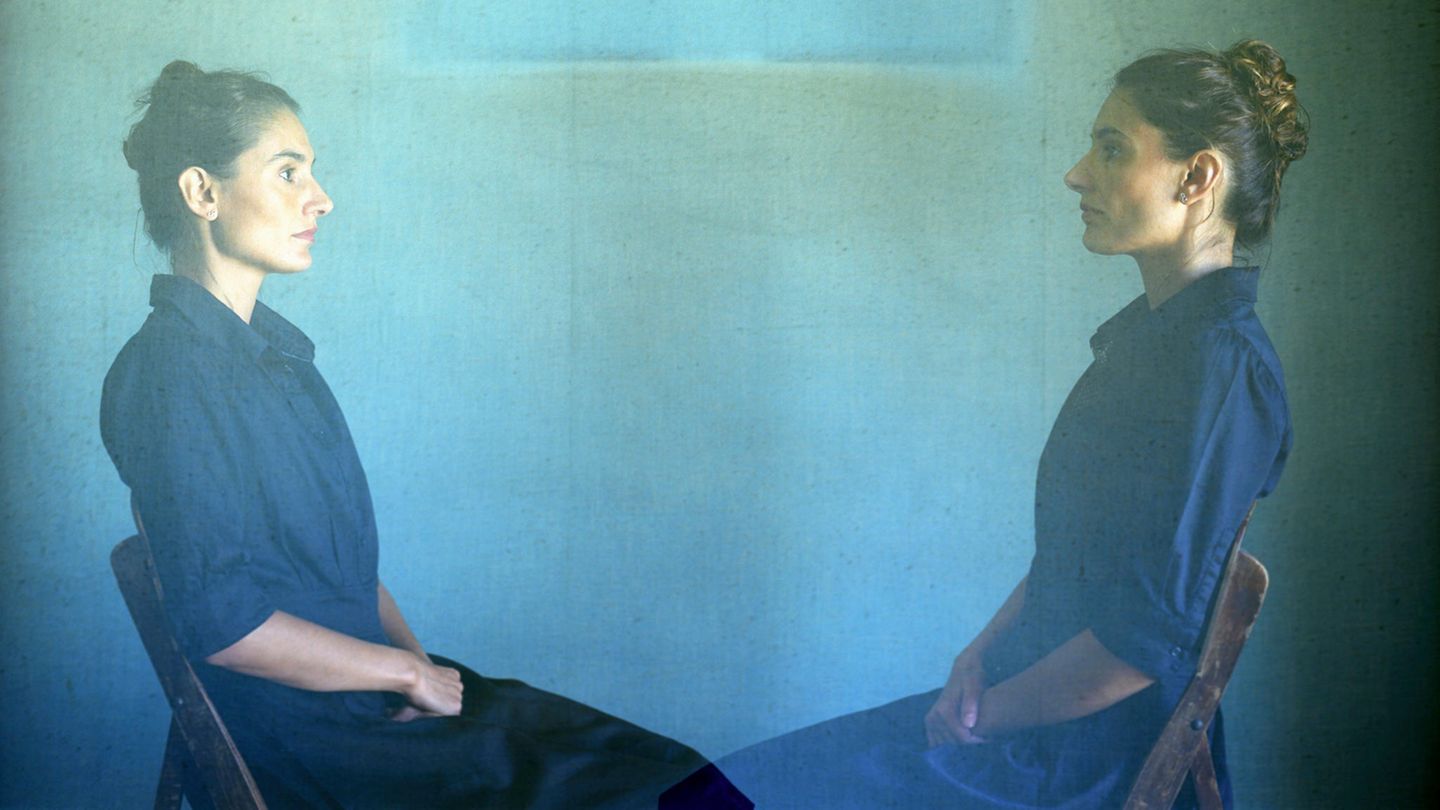 Frau sitzt auf Stuhl und ist doppelt zu sehen