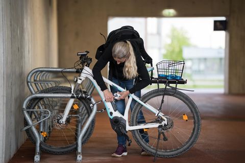 Fahrradschloss E-Bike: Frau sichert E-Bike in Tiefgarage mit Schloss