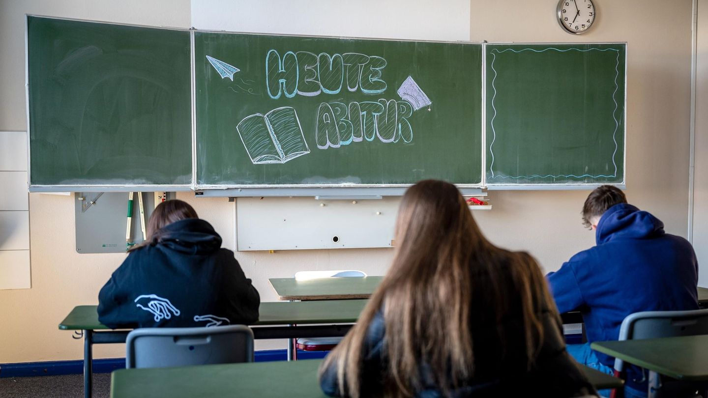 drei Schülerinnen und Schüler vor einer Tafel, auf der "Heute Abitur" steht
