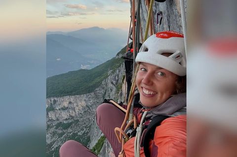 Laura Dahlmeier lächelt in die Kamera, im Hintergrund sind Berge und Sonnen untergang zu sehen.