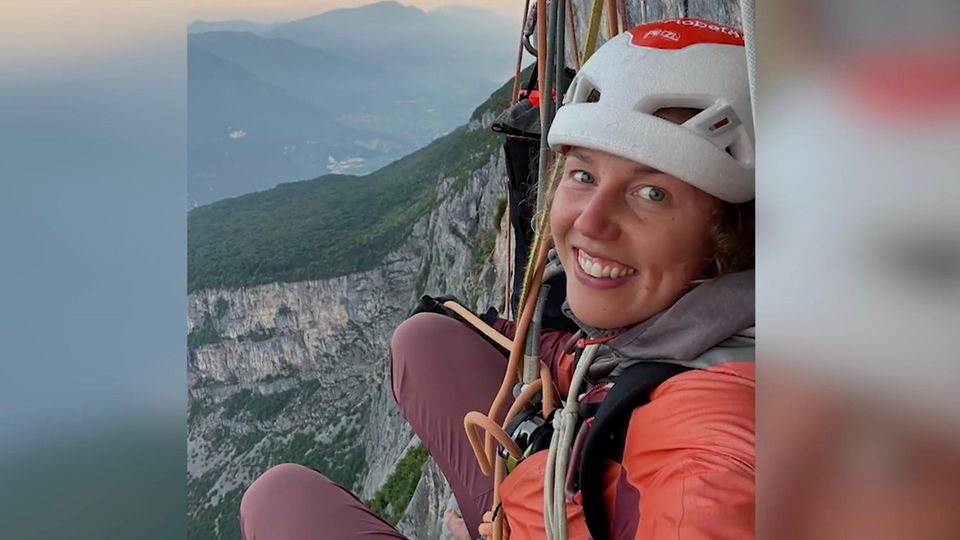 Laura Dahlmeier beim Klettern Laura Dahlmeier lächelt in die Kamera, im Hintergrund sind Berge und Sonnen untergang zu sehen.