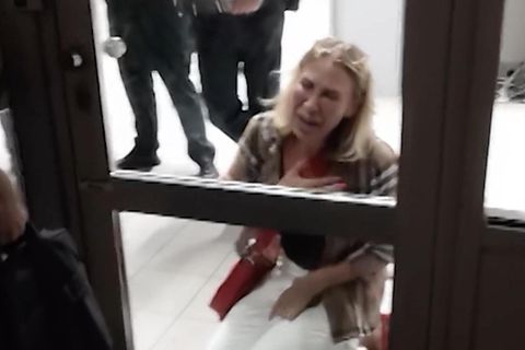 Die Gästin kniet vor einem geschlossenem Gate