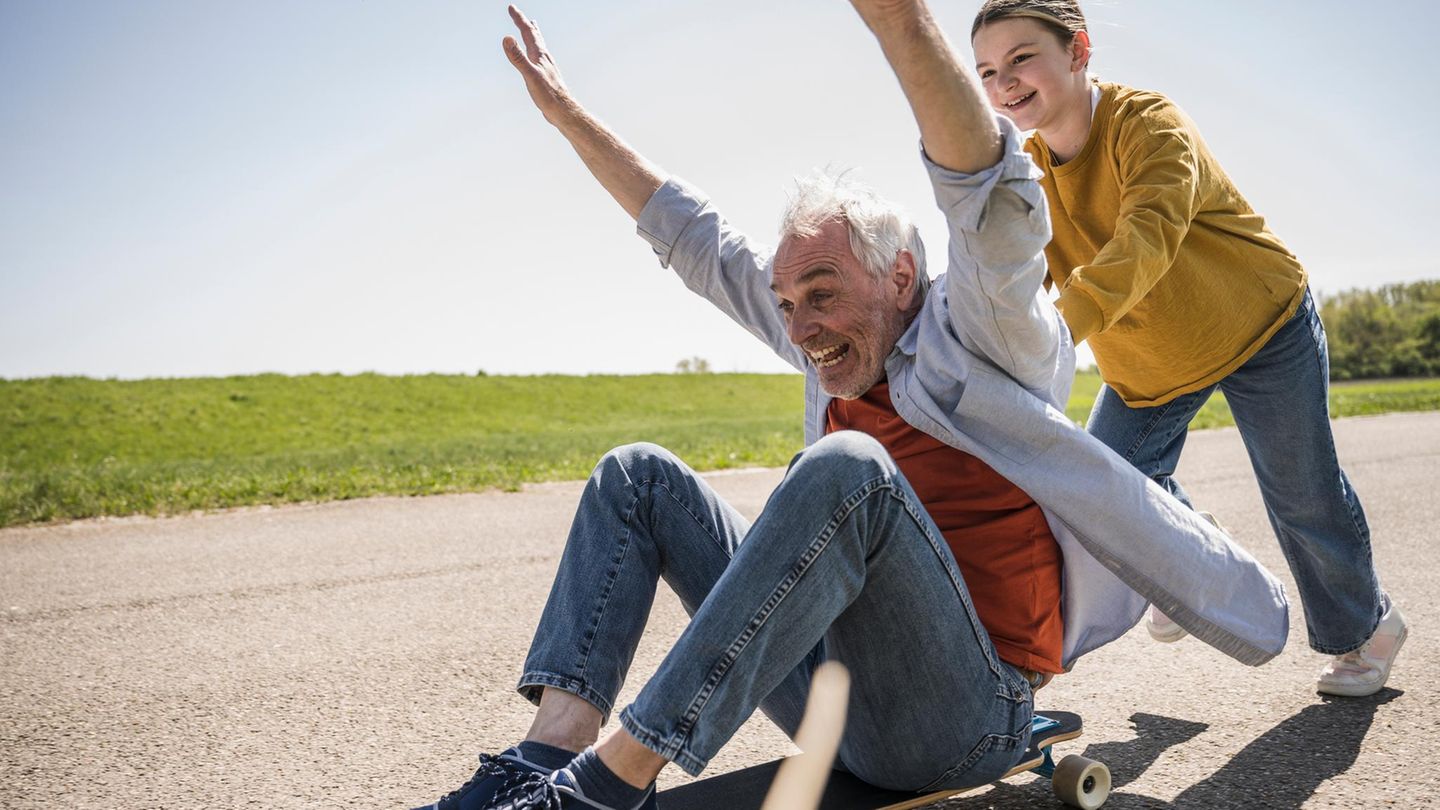 Altern: ein Junge schiebt seinen Opa auf dem Skateboard Altern: ein Junge schiebt seinen Opa auf dem Skateboard