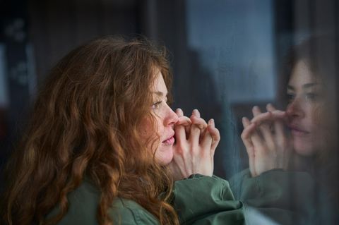 Eine Frau schaut melancholisch aus dem Fenster. Denkt sie an frühere Beziehungen?