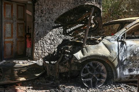 Palästinensisches Mädchen blickt auf abgebrannten Wagen in Silwad