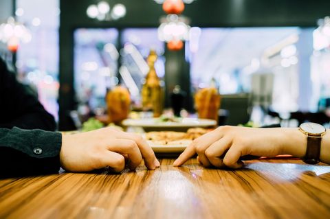 Ein Paar sitzt beim Dating am Tisch, es sind nur ihre Hände zu sehen