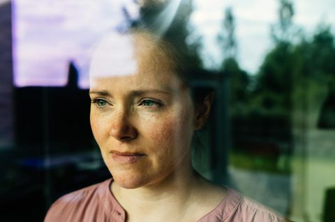 Eine Frau hatte eine Affäre und schaut nachdenklich aus dem Fenster