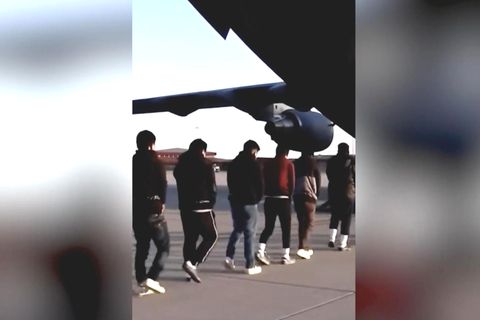 Migranten laufen in ein gefesselt in ein Flugzeug