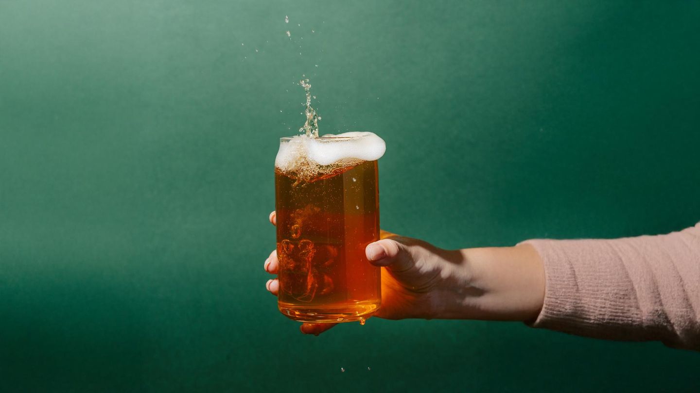 eine Hand hält ein Glas Bier