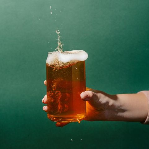 eine Hand hält ein Glas Bier