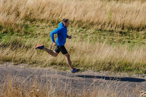 Gravel Running: Läufer auf einem Feldweg mit Laufjacke