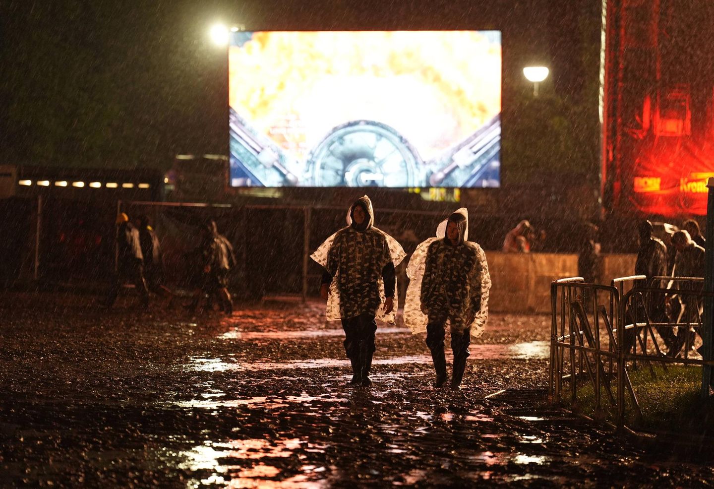 Zwei Besucher gehen im Regen über das Festivalgelände