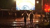 Zwei Besucher gehen im Regen über das Festivalgelände