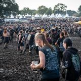 Besucher des Festivals laufen über das schlammige Gelände