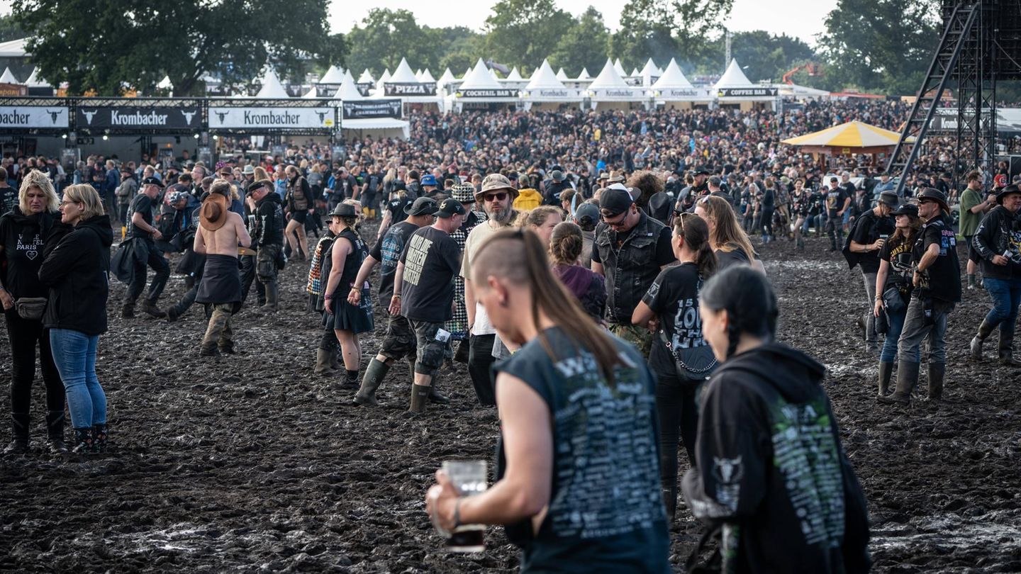 Besucher des Festivals laufen über das schlammige Gelände