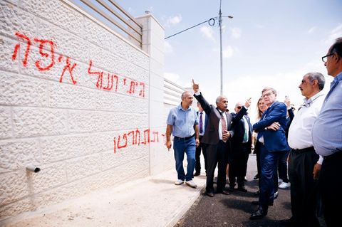 Johann Wadephul steht vor einer Wand mit Schmierereien in Taybeh
