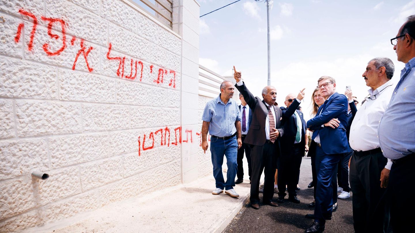 Johann Wadephul steht vor einer Wand mit Schmierereien in Taybeh