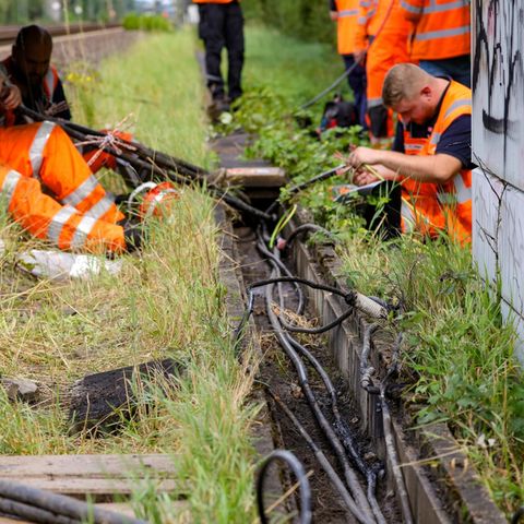 Mitarbeiter der Deutschen Bahn reparieren Kabel an der Stelle, wo der zweite Brandanschlag festgestellt wurde