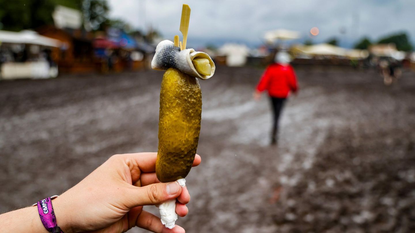 Eine Hand hält eine saure Gurke und einen Rollmops in Wacken