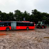 Ein Bus steckt im Matsch fest, dahinter ist ein Traktor zu sehen