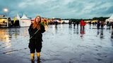 Eine Frau mit roten langen Haaren hält in Wacken eine Sonnenblume in den Händen