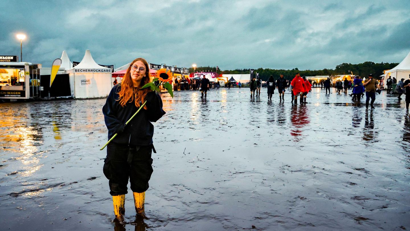Eine Frau mit roten langen Haaren hält in Wacken eine Sonnenblume in den Händen