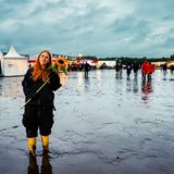 Eine Frau mit roten langen Haaren hält in Wacken eine Sonnenblume in den Händen