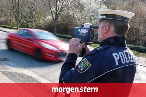 Ein Polizist misst mit einem Laserhandmessgerät während einer Geschwindigkeitskontrolle einen Autofahrer