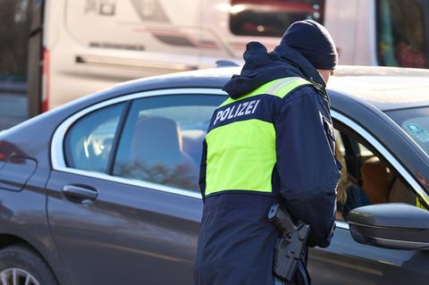 Polizist steht an einem Auto und kontrolliert den Fahrer