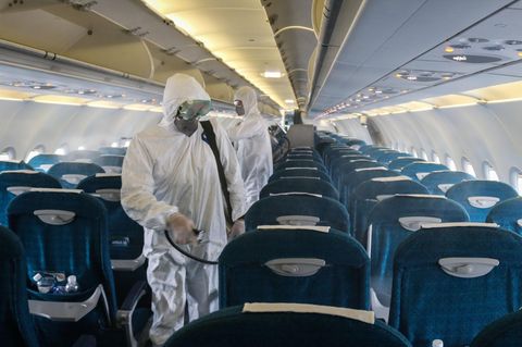 Seuchenschutzmitarbeiter versprühen in einem Flugzeug Desinfektionsmittel