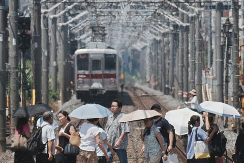 Menschen in Tokio schützen sich mit Schirmen vor der Sonne