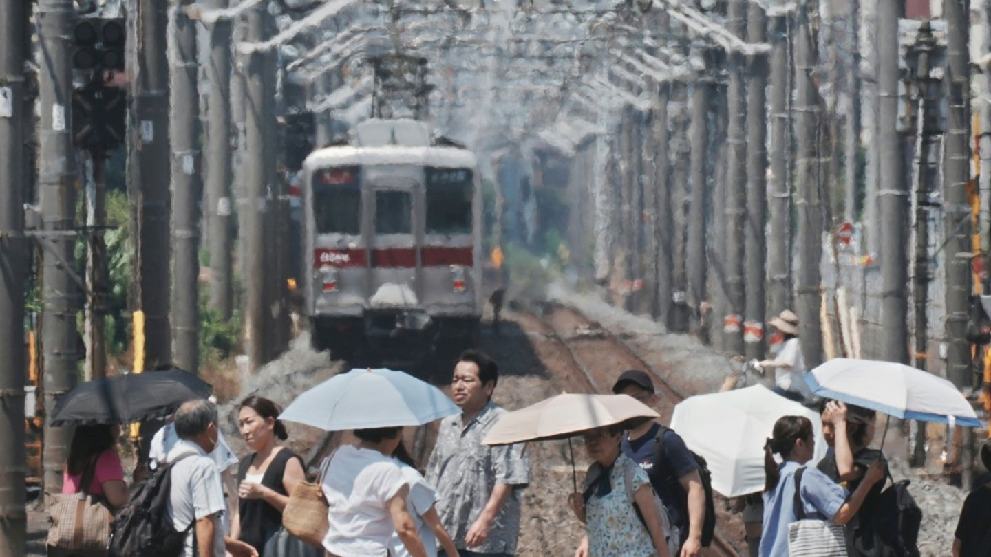 Menschen in Tokio schützen sich mit Schirmen vor der Sonne