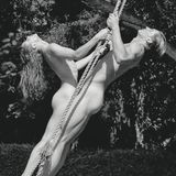 Zwei nackte Model stehen sich auf einer Schaukel gegenüber