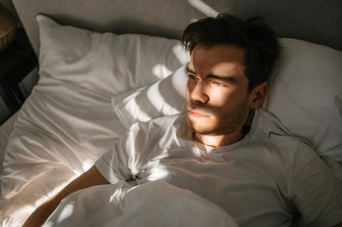 Dating-Lügner Alex Symbolbild: Ein junger Mann liegt im Bett und schaut zur Seite
