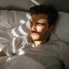 Dating-Lügner Alex Symbolbild: Ein junger Mann liegt im Bett und schaut zur Seite