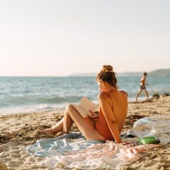 Erholung im Urlaub: Eine Frau liest ein Buch am Strand